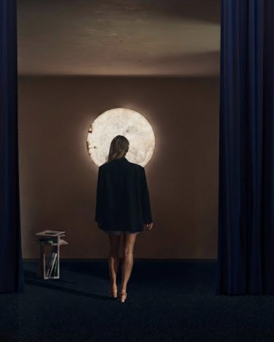 A woman walks towards MOON Ninety between dark curtains
