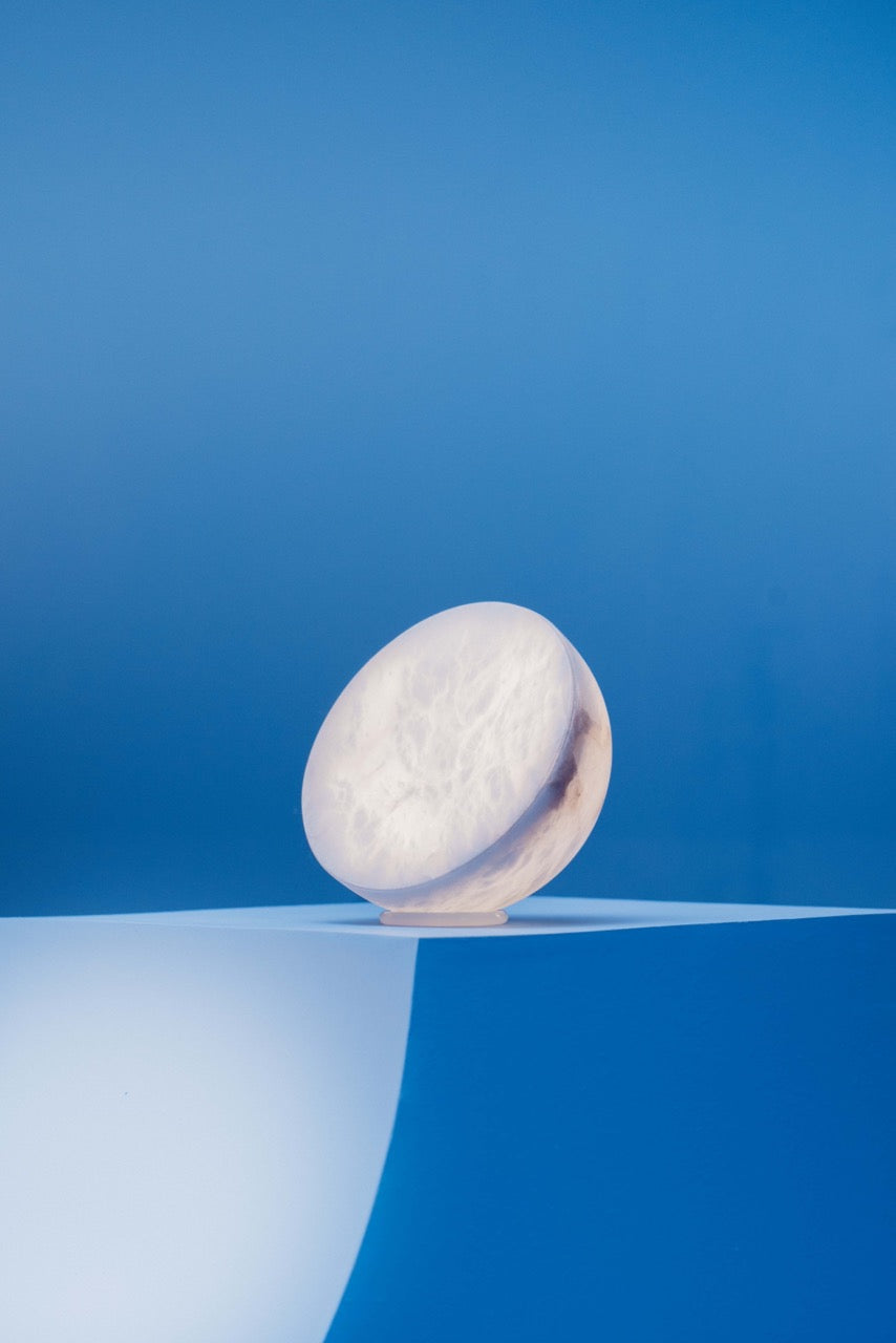 MOON Sixteen Alabaster on a blue plinth, the veins of the stone lit from inside