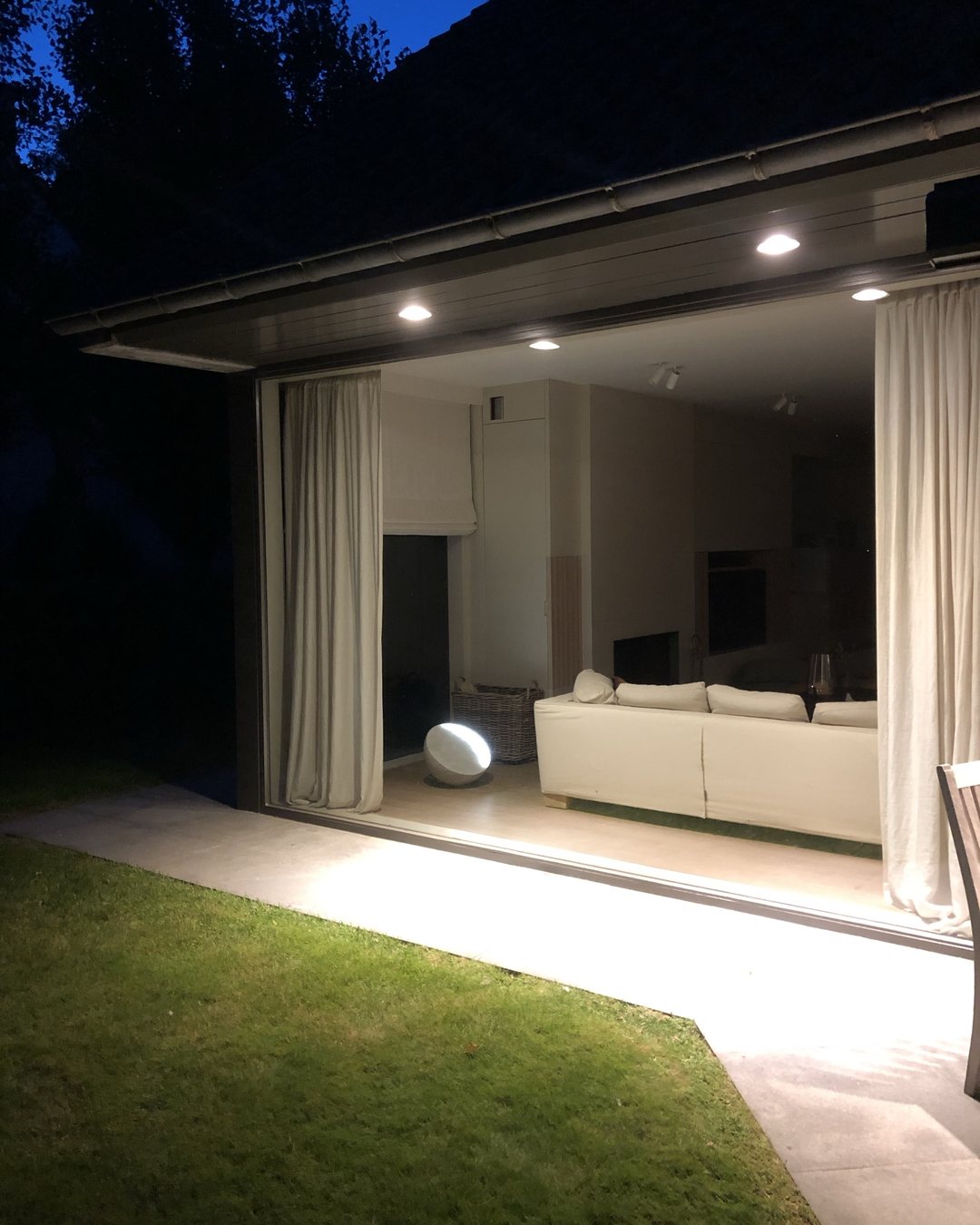 MOON Forty in einem verglasten Wohnraum, nachts vom Garten aus gesehen.