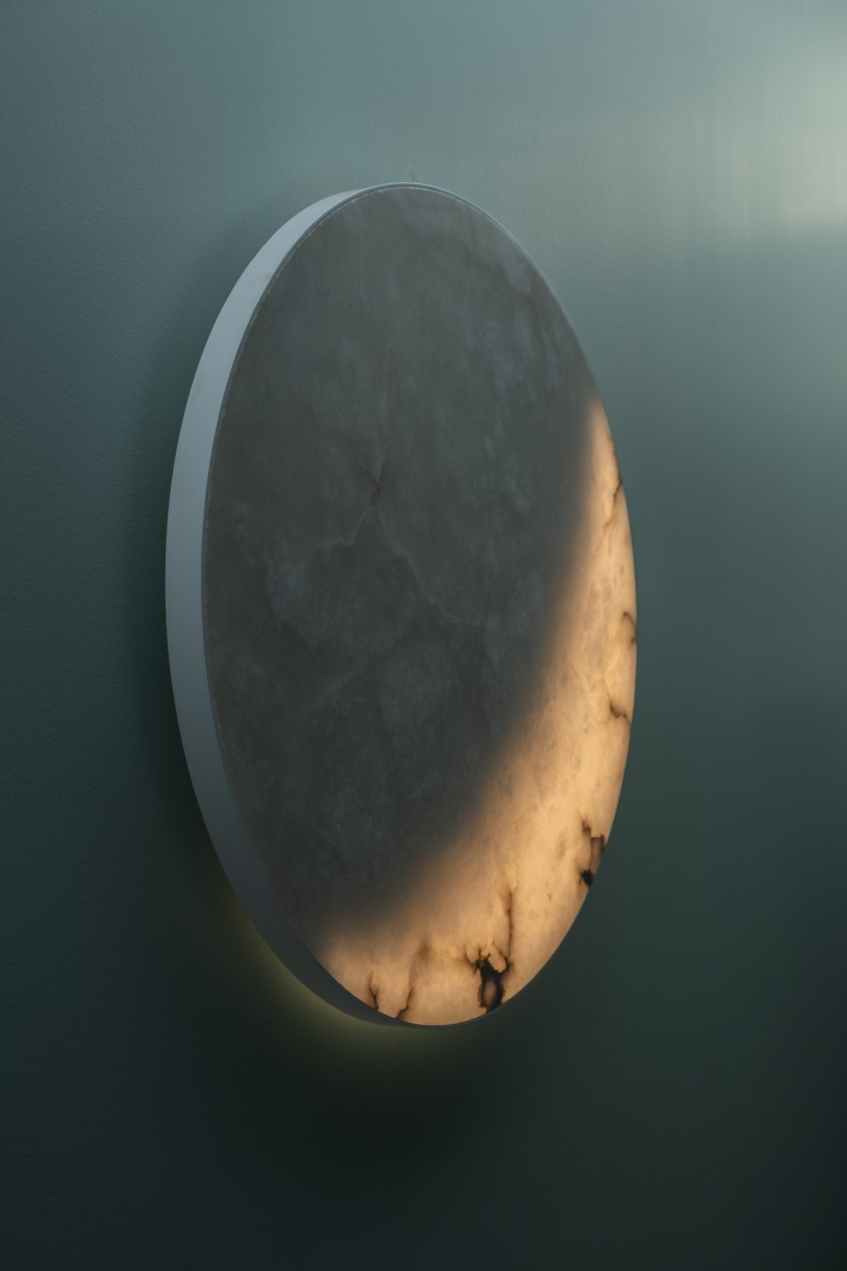 MOON Ninety from the side on a grey-teal wall, a crescent lit: the stone is 70 mm deep